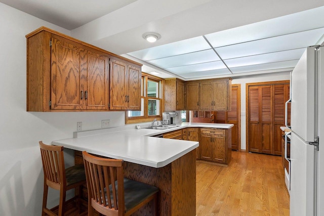 430 Fairview Way, Shawano, WI 54166 - kitchen with a peninsula, freestanding refrigerator, a sink, brown cabinets, and light wood-type flooring
