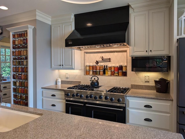 109 Doty St, Fremont, WI 54940 - kitchen featuring double oven range, wall chimney range hood, white cabinets, tasteful backsplash, and ornamental molding