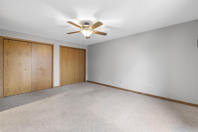 167 W Paradise Dr, West Bend, WI 53095 - unfurnished bedroom with two closets, light colored carpet, baseboards, and a ceiling fan