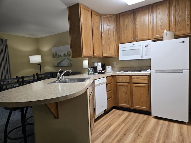 111 Center St Unit 355, Lake Geneva, WI 53147 - kitchen with white appliances, a sink, a peninsula, light wood-type flooring, and a kitchen breakfast bar