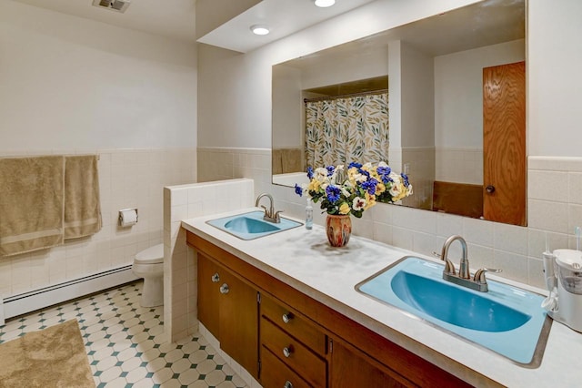7628 W Mineral Point Rd, Verona, WI 53593 - bathroom featuring baseboard heating, tile walls, toilet, a wainscoted wall, and double vanity