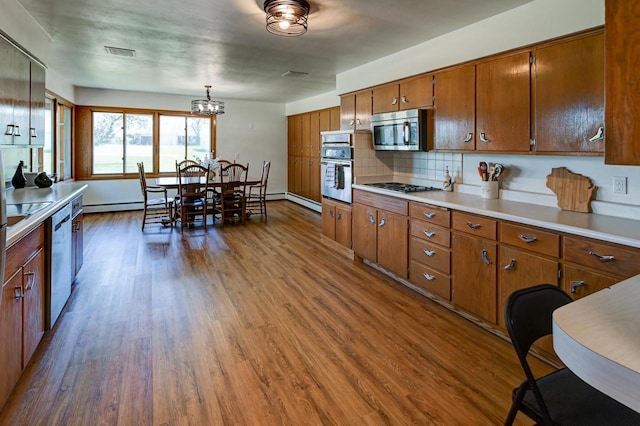 7628 W Mineral Point Rd, Verona, WI 53593 - kitchen with appliances with stainless steel finishes, a baseboard heating unit, brown cabinetry, and dark wood-style flooring