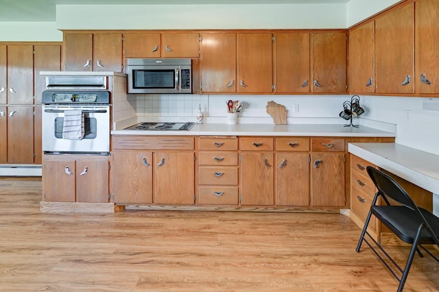 7628 W Mineral Point Rd, Verona, WI 53593 - kitchen featuring stainless steel appliances, light countertops, light wood-style flooring, and brown cabinetry