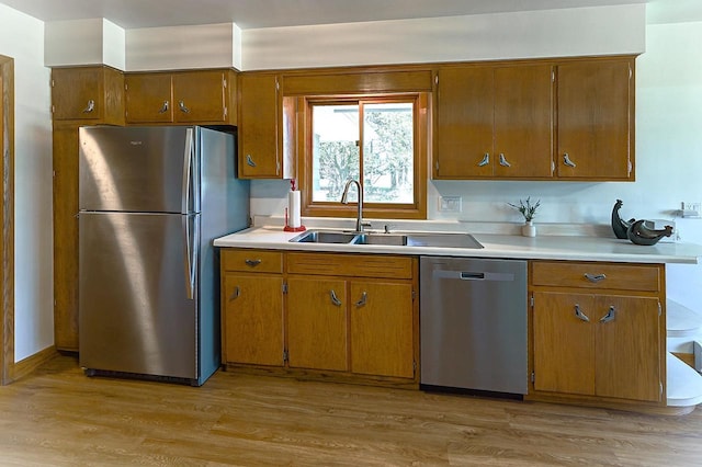 7628 W Mineral Point Rd, Verona, WI 53593 - kitchen featuring appliances with stainless steel finishes, a sink, light countertops, brown cabinets, and light wood-style flooring