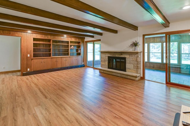 7628 W Mineral Point Rd, Verona, WI 53593 - unfurnished living room with wood finished floors, beam ceiling, baseboards, a stone fireplace, and built in features