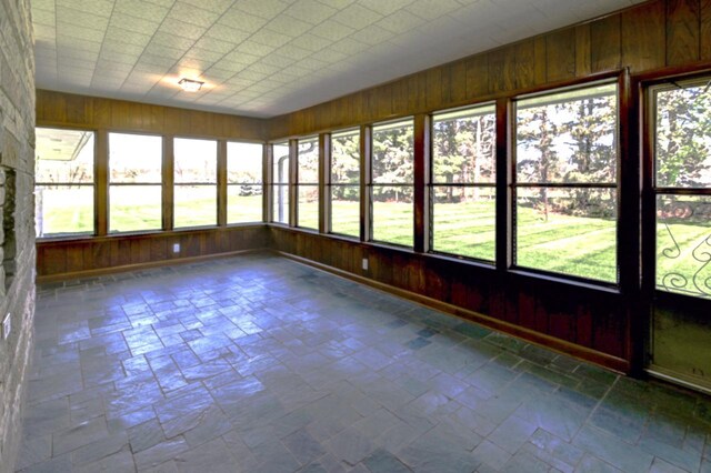 7628 W Mineral Point Rd, Verona, WI 53593 - unfurnished sunroom with wooden walls, healthy amount of natural light, and stone tile flooring