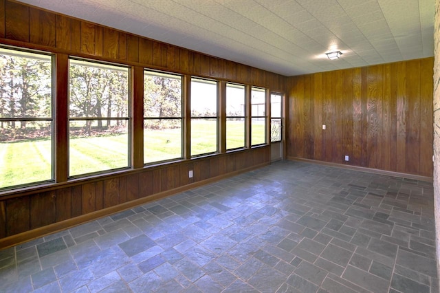 7628 W Mineral Point Rd, Verona, WI 53593 - empty room featuring wood walls, baseboards, and stone finish flooring