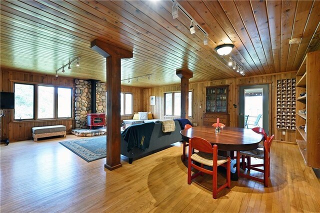 12642 Paddock Rd, Hayward, WI 54843 - dining space featuring track lighting, a wood stove, wood walls, plenty of natural light, and light wood-type flooring