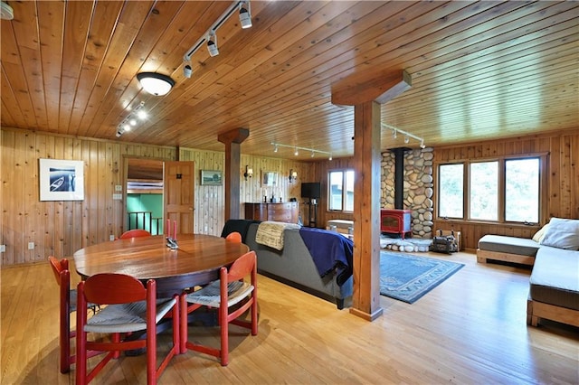 12642 Paddock Rd, Hayward, WI 54843 - dining area featuring track lighting, a wood stove, wood walls, light wood-type flooring, and wooden ceiling