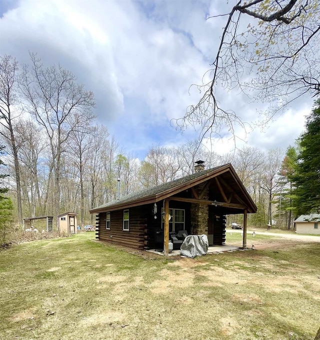 N18355 Big Bear Rd, Pembine, WI 54156 - view of side of property with log exterior, a chimney, an outbuilding, and a lawn