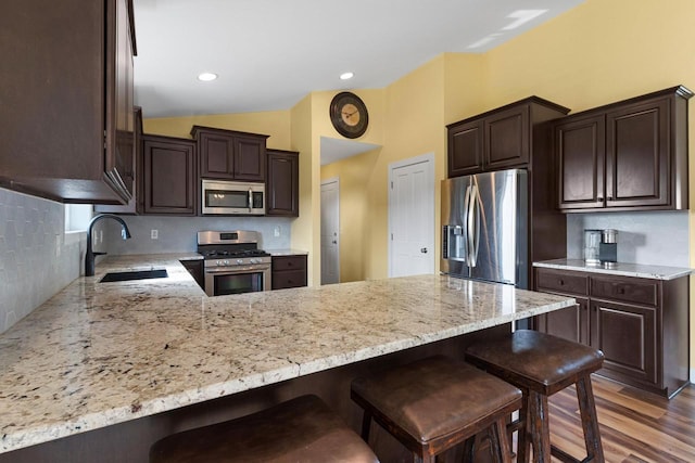 3410 Tulip Trl, Appleton, WI 54913 - kitchen with appliances with stainless steel finishes, a sink, a peninsula, dark brown cabinetry, and vaulted ceiling