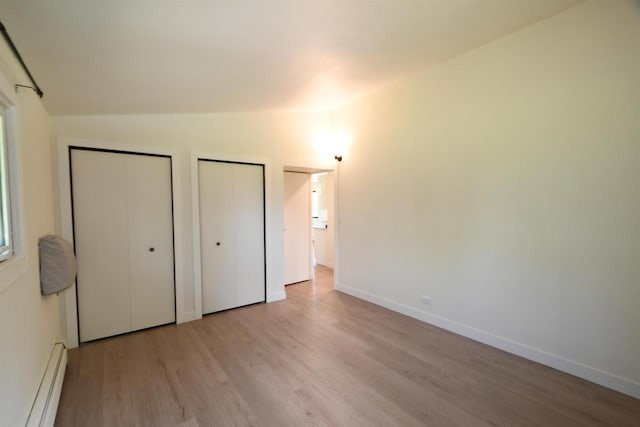 W13414 Liner Rd, Brandon, WI 53919 - unfurnished bedroom featuring a baseboard heating unit, two closets, wood finished floors, and baseboards