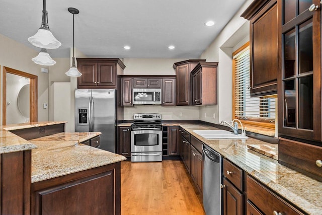 N8454 Muirfield Way, Menasha, WI 54952 - kitchen with stainless steel appliances, a sink, dark brown cabinets, pendant lighting, and light wood-type flooring
