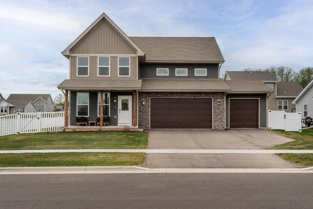241 E Hubert St, Edgerton, WI 53534 - craftsman house featuring a gate, covered porch, asphalt driveway, roof with shingles, and an attached garage