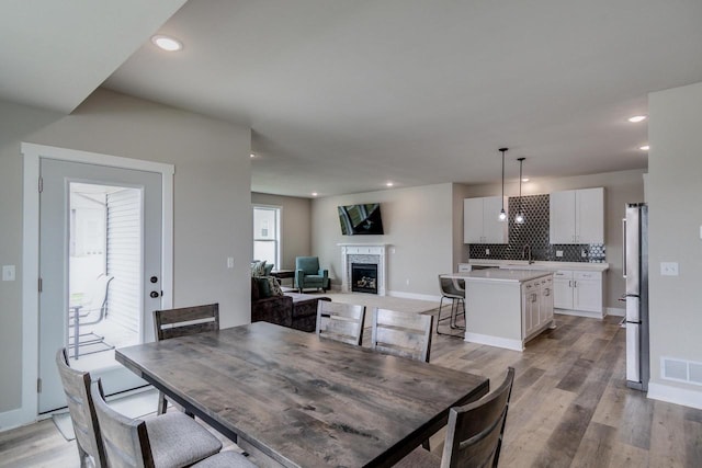 241 E Hubert St, Edgerton, WI 53534 - dining space featuring light wood-style floors, a premium fireplace, recessed lighting, and baseboards