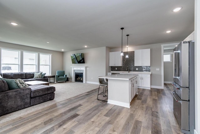 241 E Hubert St, Edgerton, WI 53534 - kitchen with freestanding refrigerator, open floor plan, light countertops, a kitchen breakfast bar, and white cabinets