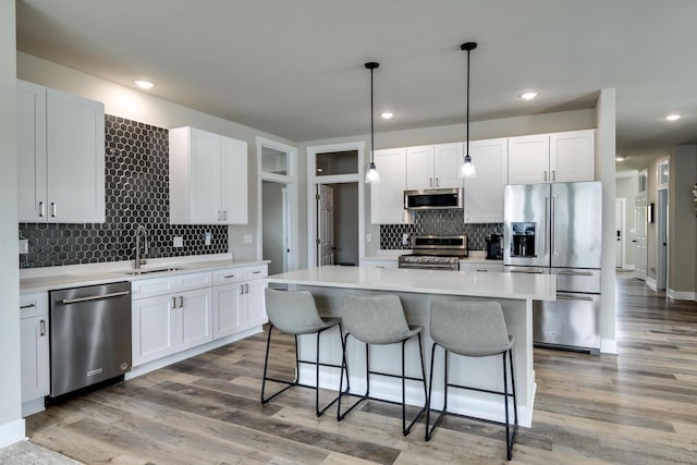 241 E Hubert St, Edgerton, WI 53534 - kitchen with stainless steel appliances, a sink, decorative backsplash, a breakfast bar area, and recessed lighting