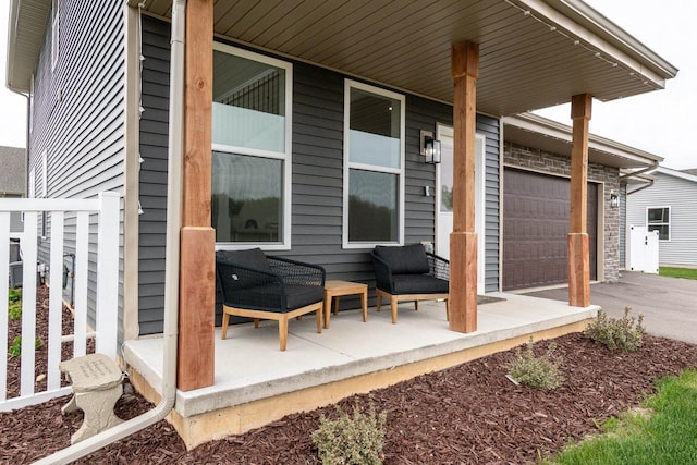 241 E Hubert St, Edgerton, WI 53534 - view of patio / terrace with a garage, asphalt driveway, and a porch