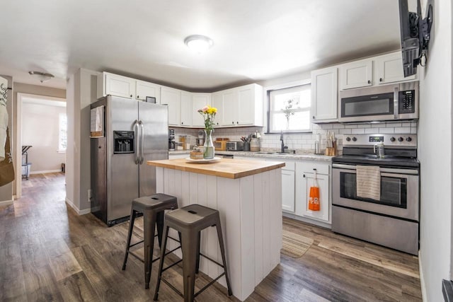 1578 Cass St, Green Bay, WI 54302 - kitchen with stainless steel appliances, butcher block countertops, a breakfast bar, white cabinets, and decorative backsplash