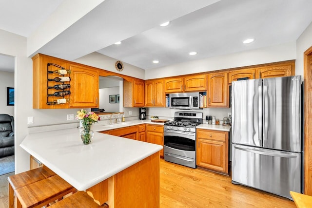 4619 Stonebridge Dr, Racine, WI 53404 - kitchen featuring appliances with stainless steel finishes, a sink, light countertops, a kitchen breakfast bar, and brown cabinetry
