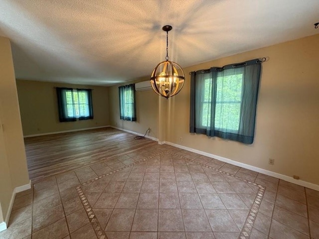 228227 County Road Y, Birnamwood, WI 54414 - tiled empty room with a chandelier, baseboards, a wall mounted AC, a textured ceiling, and inlaid floor details