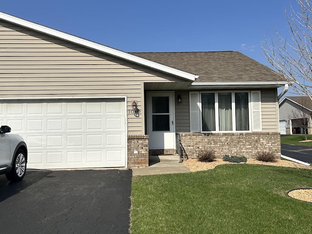 1010 Whispering Winds Pl, Onalaska, WI 54650 - ranch-style home with brick siding, roof with shingles, a front lawn, an attached garage, and asphalt driveway