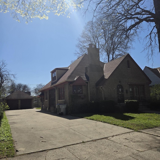 view of front of home with a garage, an outdoor structure, brick siding, and a chimney