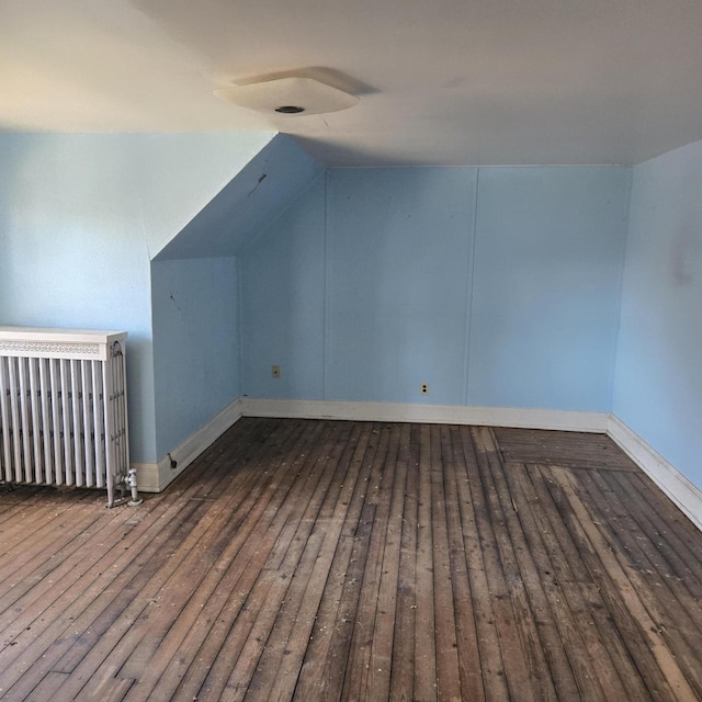 additional living space with hardwood / wood-style floors, baseboards, and vaulted ceiling