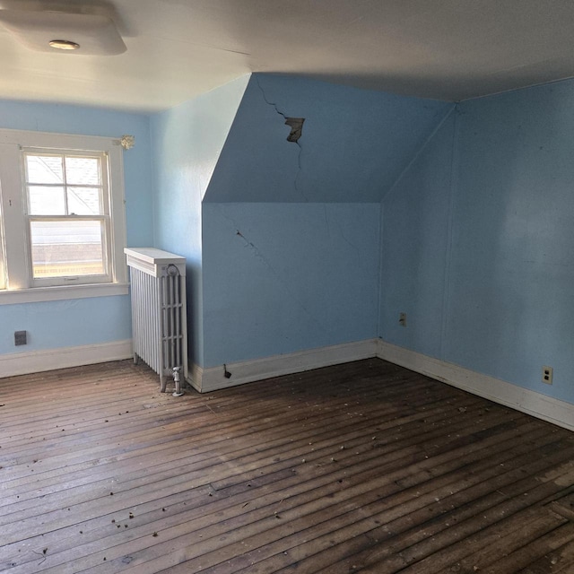 additional living space featuring radiator, hardwood / wood-style floors, lofted ceiling, and baseboards