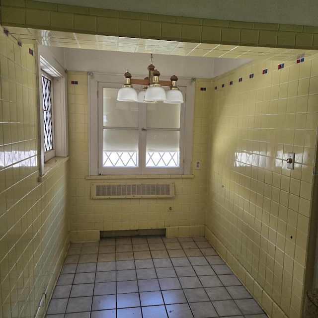 unfurnished dining area featuring light tile patterned floors, radiator heating unit, and tile walls