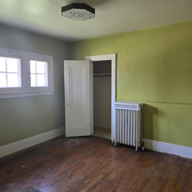 unfurnished bedroom with radiator heating unit, hardwood / wood-style floors, and baseboards