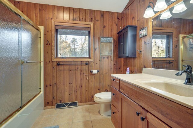 1948 Wild Life Ln, Eagle River, WI 54521 - bathroom with tile patterned flooring, wooden walls, toilet, vanity, and enclosed tub / shower combo