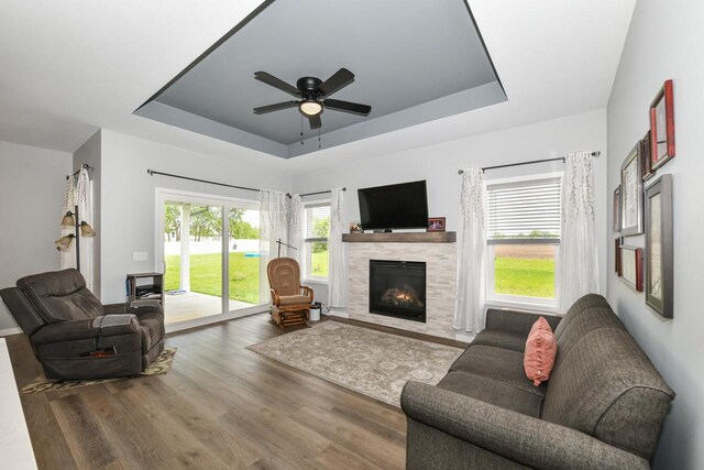 5150 Fairmont Dr, Milton, WI 53563 - living room with a tray ceiling, wood finished floors, a tiled fireplace, and ceiling fan