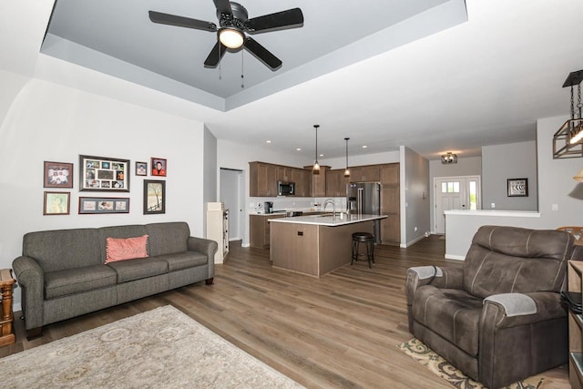 5150 Fairmont Dr, Milton, WI 53563 - living room featuring wood finished floors, a ceiling fan, a tray ceiling, baseboards, and recessed lighting