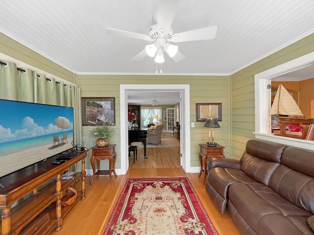 living area featuring ceiling fan, crown molding, wood finished floors, and wooden walls