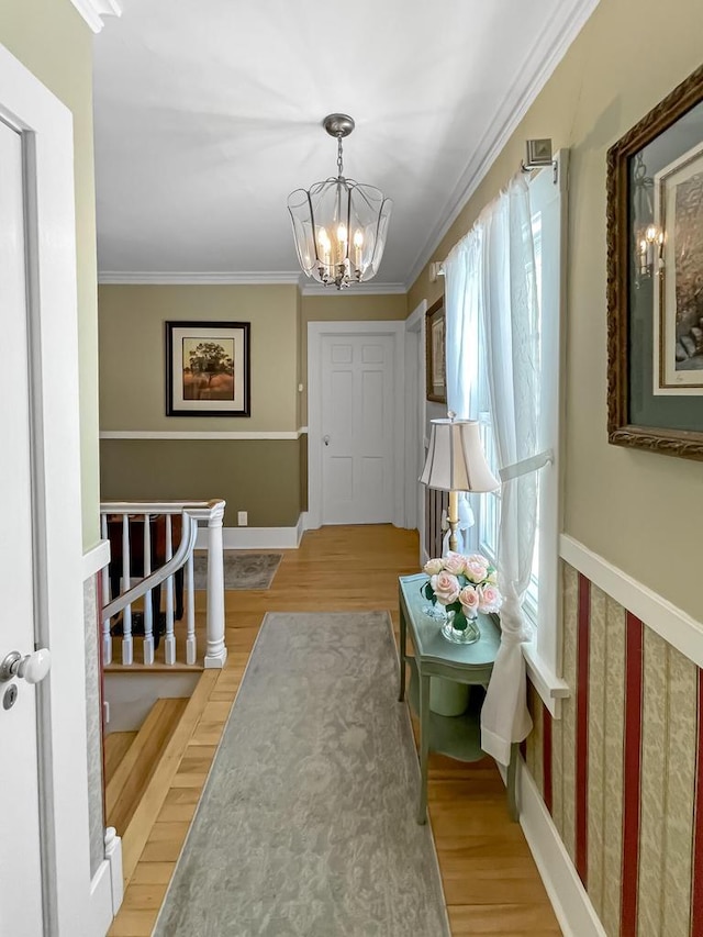 foyer entrance featuring a chandelier, light wood-type flooring, crown molding, and baseboards