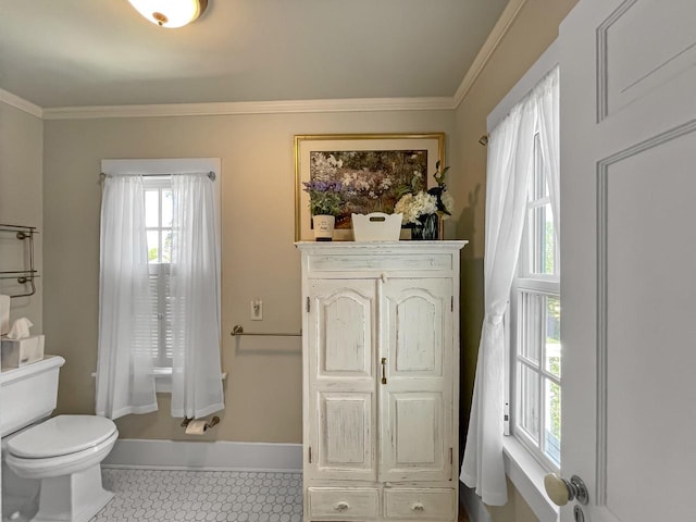 bathroom featuring toilet, ornamental molding, and baseboards