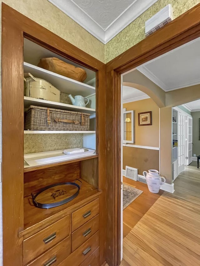 detailed view of ornamental molding, wood finished floors, baseboards, and arched walkways