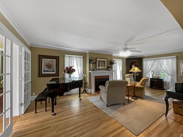 living room with crown molding, plenty of natural light, light wood-style flooring, and a fireplace
