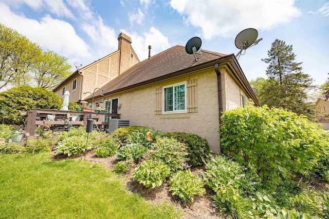 14 Golf Course Rd, Madison, WI 53704 - view of side of home featuring a chimney, stucco siding, central AC, a yard, and a shingled roof