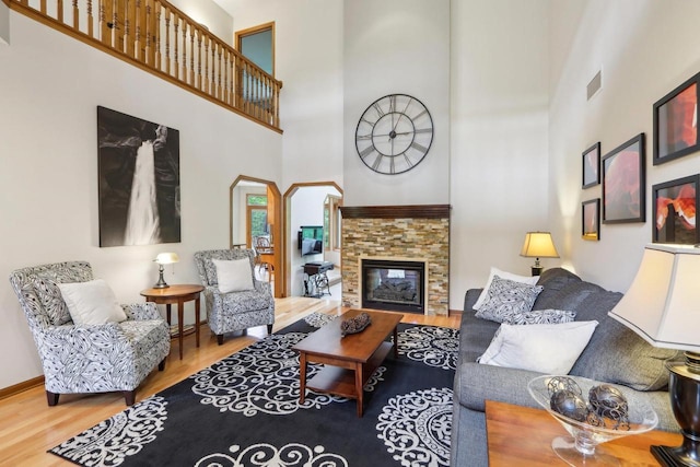 1816 Blue Ridge Trl, Waunakee, WI 53597 - living area with a towering ceiling, wood finished floors, a stone fireplace, arched walkways, and baseboards