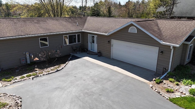 N1423 Silver Canoe Rd, Keshena, WI 54135 - ranch-style home with roof with shingles, asphalt driveway, and a garage