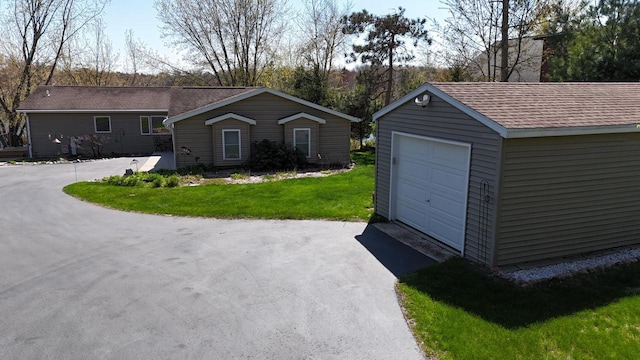 N1423 Silver Canoe Rd, Keshena, WI 54135 - view of front of house featuring a garage, an outdoor structure, asphalt driveway, a front lawn, and a chimney