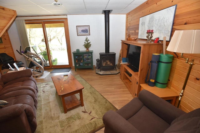 N1423 Silver Canoe Rd, Keshena, WI 54135 - living room with a wood stove, light wood finished floors, wood walls, and a paneled ceiling