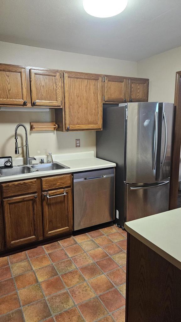 7040 Mariner Dr Unit 103, Mount Pleasant, WI 53406 - kitchen featuring stainless steel appliances, a sink, light countertops, and stone tile floors