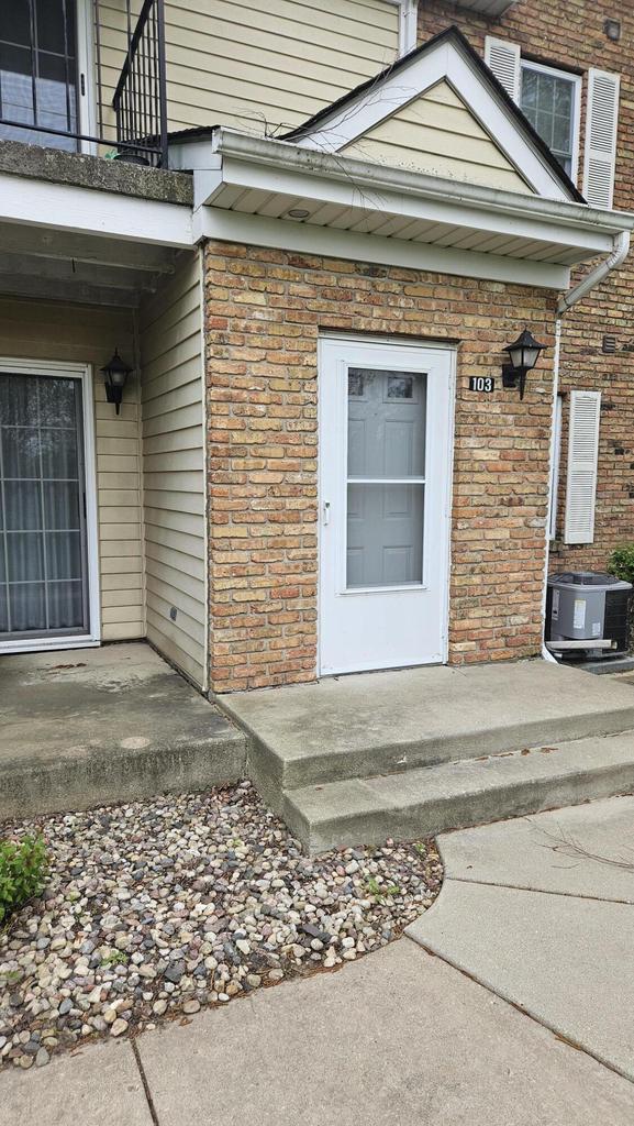7040 Mariner Dr Unit 103, Mount Pleasant, WI 53406 - doorway to property with cooling unit, brick siding, and a balcony