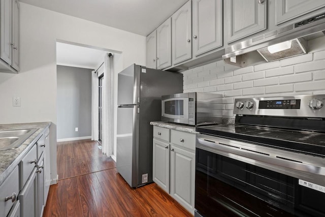 6548 N Bourbon St, Milwaukee, WI 53224 - kitchen with appliances with stainless steel finishes, under cabinet range hood, tasteful backsplash, dark wood finished floors, and white cabinetry