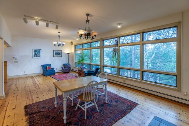 8395 Woolpy Dr, Minocqua, WI 54548 - dining room featuring baseboard heating, a chandelier, light wood-style floors, and plenty of natural light