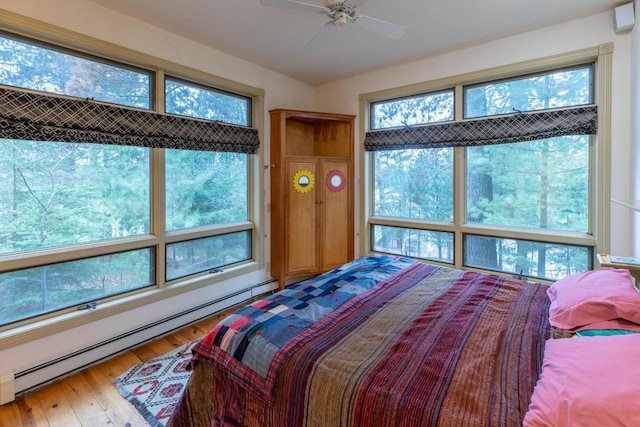 8395 Woolpy Dr, Minocqua, WI 54548 - bedroom with a baseboard radiator, multiple windows, hardwood / wood-style floors, and ceiling fan