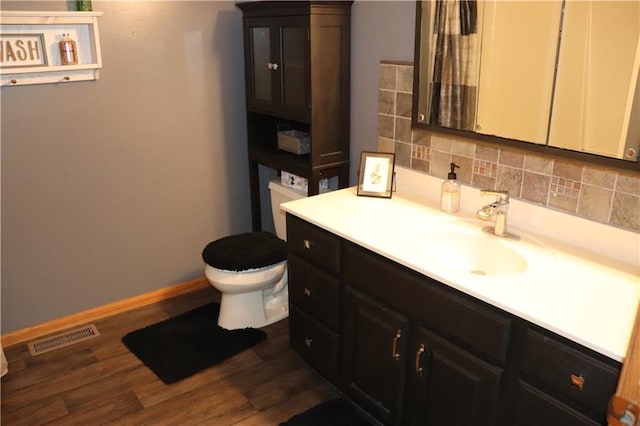 3530 Briarcrest Dr, Eau Claire, WI 54701 - bathroom featuring toilet, vanity, baseboards, wood finished floors, and backsplash